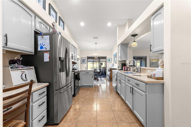 kitchen featuring light tile patterned floors, gray cabinets, hanging light fixtures, light countertops, and appliances with stainless steel finishes