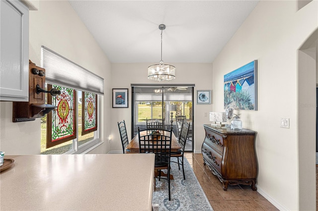 dining space with light tile patterned floors, a notable chandelier, baseboards, and lofted ceiling