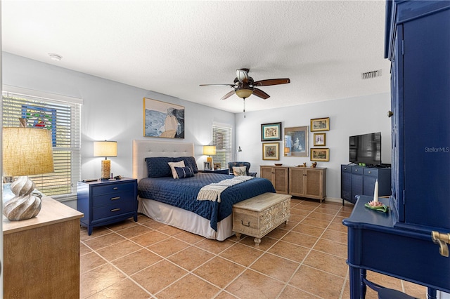 bedroom featuring light tile patterned flooring, visible vents, a textured ceiling, and a ceiling fan