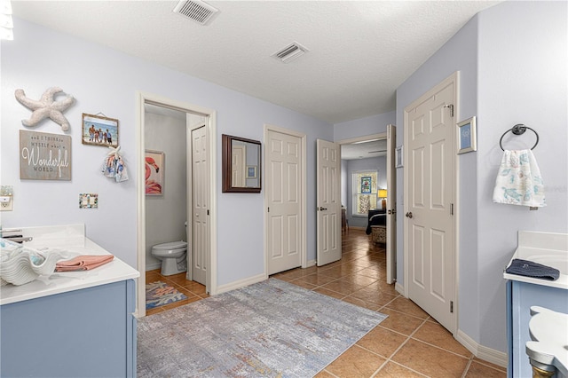 bathroom with tile patterned floors, toilet, visible vents, and a textured ceiling