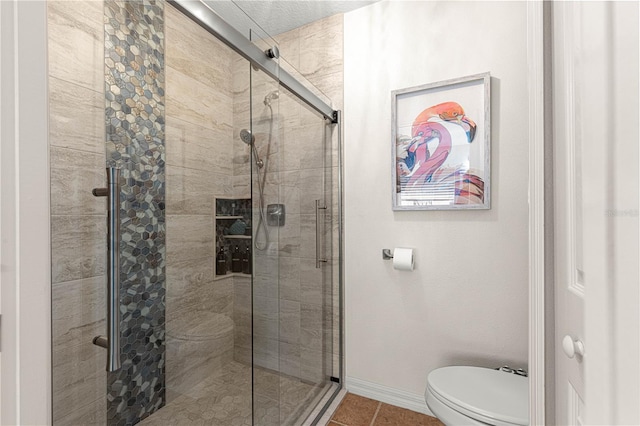 full bathroom with tile patterned flooring, a stall shower, toilet, and baseboards