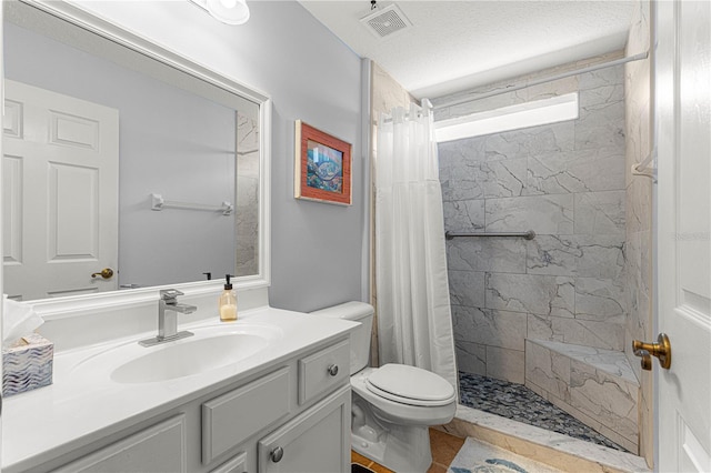 full bathroom with visible vents, toilet, a textured ceiling, tiled shower, and vanity