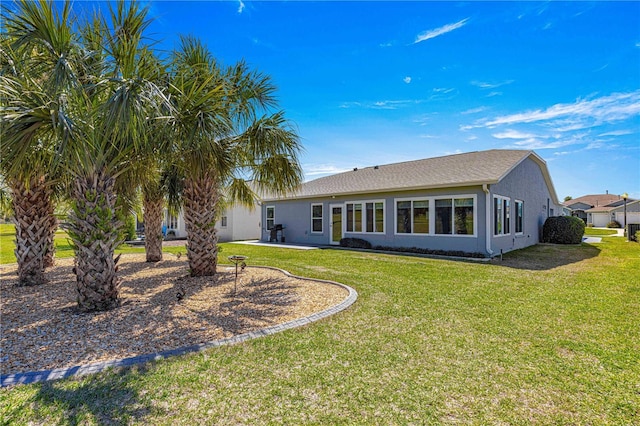 rear view of property with a patio area, stucco siding, and a yard