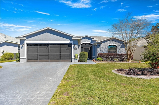 single story home featuring a front lawn, decorative driveway, an attached garage, and stucco siding