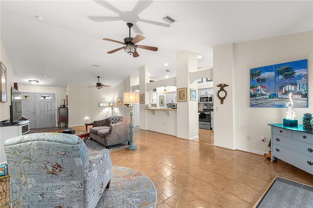 living area featuring visible vents, baseboards, ceiling fan, lofted ceiling, and arched walkways