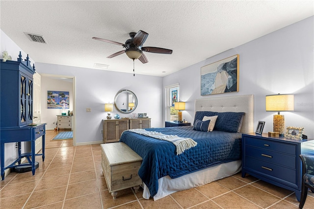 bedroom featuring light tile patterned floors, a ceiling fan, baseboards, visible vents, and a textured ceiling