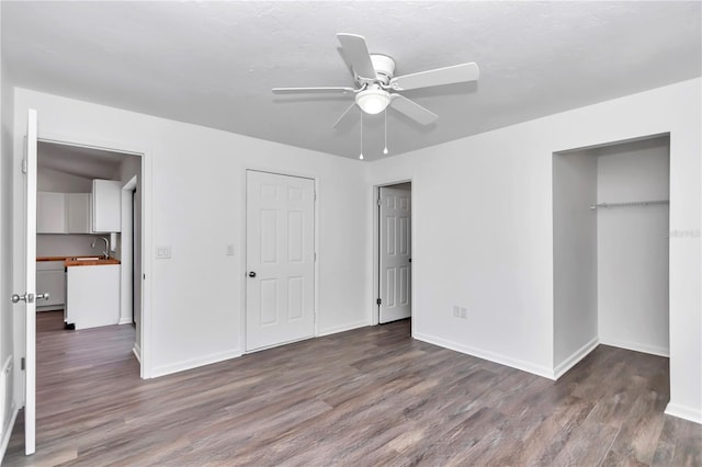 unfurnished bedroom featuring multiple closets, ceiling fan, dark wood-type flooring, and sink