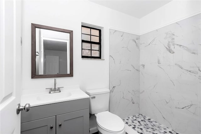 bathroom with vanity, toilet, and a tile shower