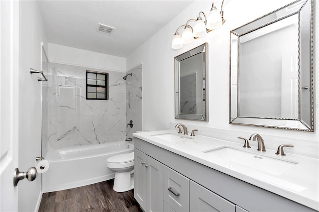 full bathroom featuring hardwood / wood-style floors, vanity, toilet, and tiled shower / bath