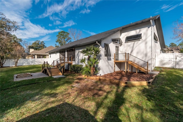 rear view of house with a yard and an outdoor fire pit