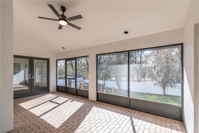 unfurnished sunroom featuring ceiling fan, plenty of natural light, and vaulted ceiling