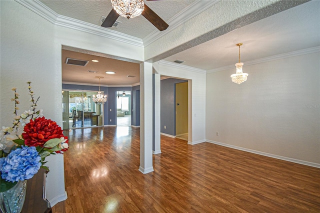 empty room featuring hardwood / wood-style flooring, ceiling fan with notable chandelier, ornamental molding, and a textured ceiling