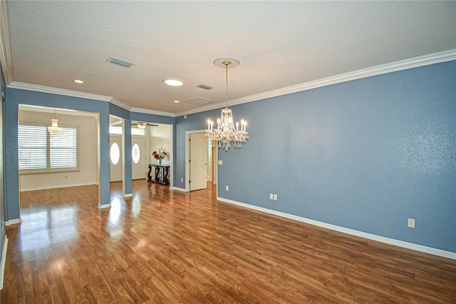 spare room with ceiling fan with notable chandelier, dark hardwood / wood-style floors, ornate columns, and crown molding