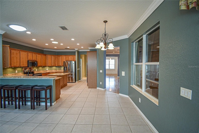 kitchen featuring a kitchen breakfast bar, ornamental molding, appliances with stainless steel finishes, light tile patterned flooring, and a chandelier