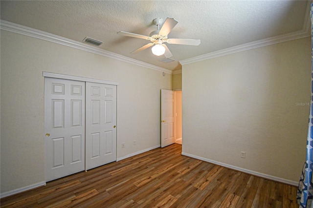 unfurnished bedroom with ornamental molding, a textured ceiling, ceiling fan, dark wood-type flooring, and a closet