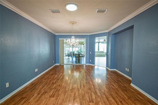 unfurnished dining area featuring hardwood / wood-style flooring, crown molding, a textured ceiling, and an inviting chandelier