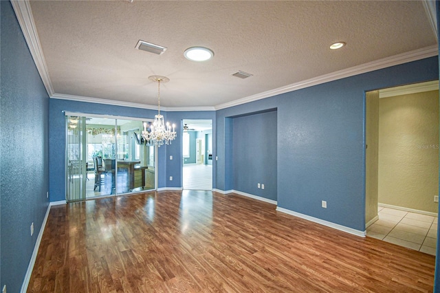 unfurnished dining area with a chandelier, a textured ceiling, hardwood / wood-style flooring, and ornamental molding