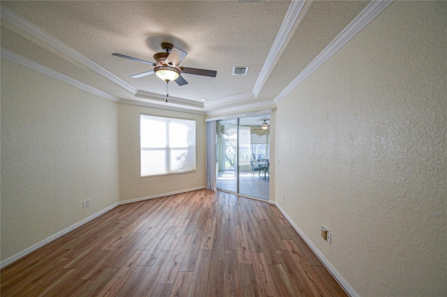 spare room featuring a tray ceiling, ceiling fan, hardwood / wood-style floors, and ornamental molding