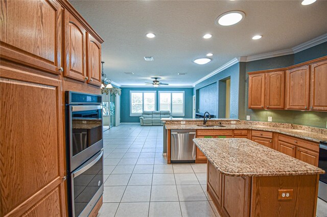 kitchen with ceiling fan, a center island, sink, stainless steel appliances, and ornamental molding