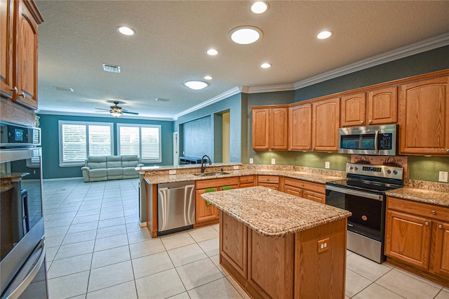 kitchen featuring ceiling fan, a kitchen island, stainless steel appliances, and ornamental molding