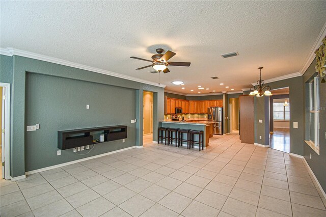 kitchen with light tile patterned floors, ceiling fan with notable chandelier, stainless steel appliances, and ornamental molding