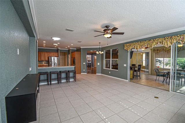 unfurnished living room featuring a textured ceiling, crown molding, light tile patterned floors, and ceiling fan with notable chandelier