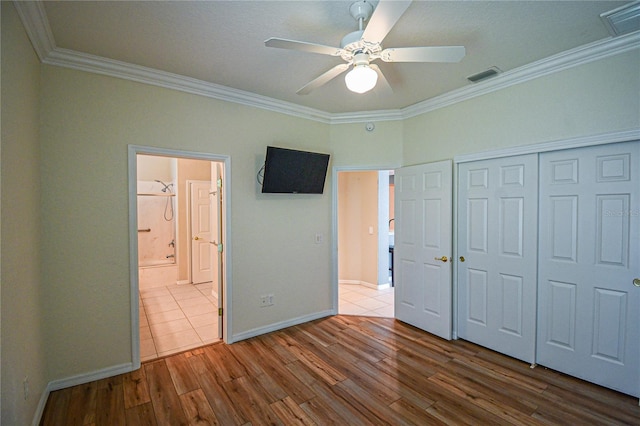 unfurnished bedroom with ensuite bath, ceiling fan, ornamental molding, a closet, and light wood-type flooring