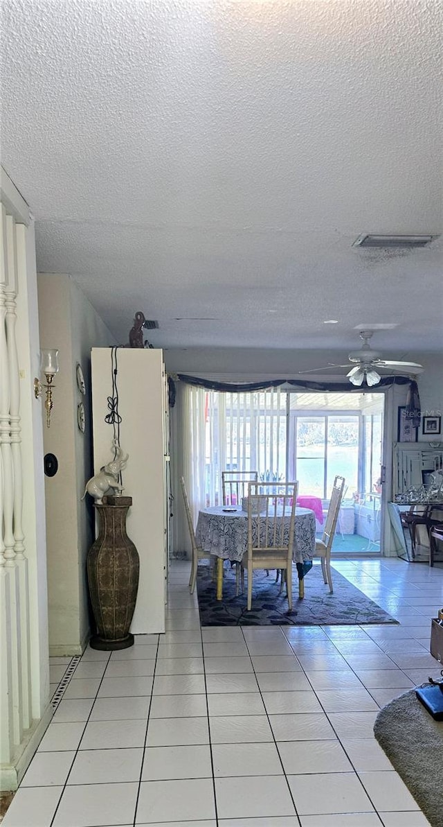 dining space with ceiling fan, light tile patterned flooring, and a textured ceiling