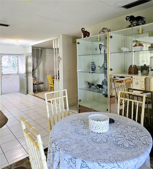 dining space featuring light tile patterned floors and a textured ceiling