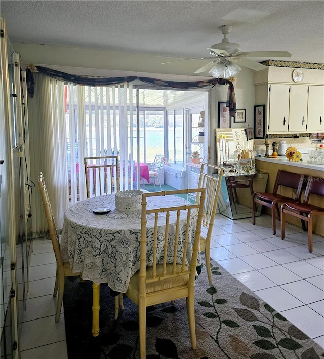 dining room featuring ceiling fan, light tile patterned floors, and a textured ceiling