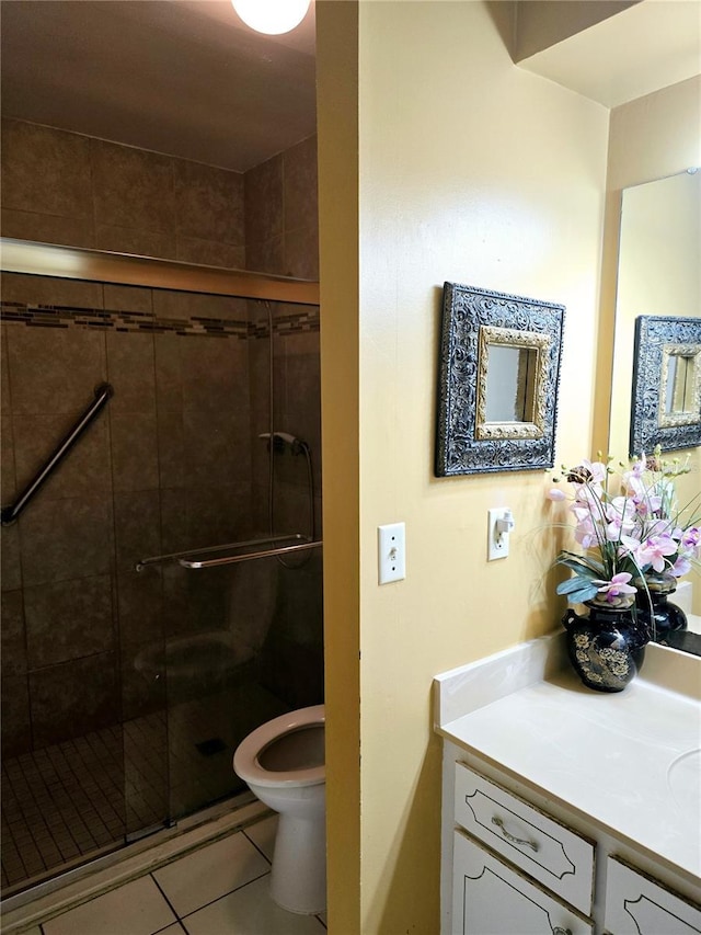 bathroom featuring toilet, vanity, tile patterned floors, and a shower with door