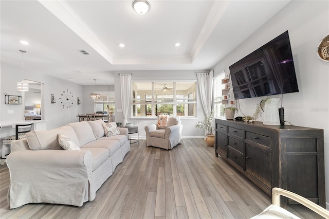 living room featuring a tray ceiling, crown molding, and light hardwood / wood-style floors