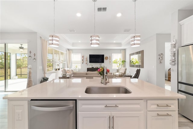 kitchen featuring white cabinetry, sink, a raised ceiling, a kitchen island with sink, and appliances with stainless steel finishes