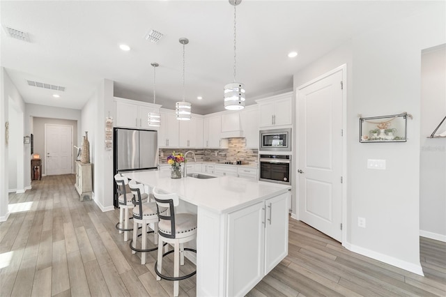 kitchen with white cabinetry, sink, an island with sink, and appliances with stainless steel finishes