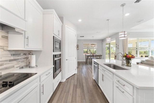 kitchen featuring sink, hanging light fixtures, an island with sink, white cabinetry, and stainless steel appliances