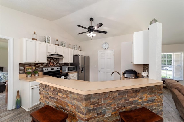 kitchen with ceiling fan, backsplash, vaulted ceiling, white cabinets, and appliances with stainless steel finishes