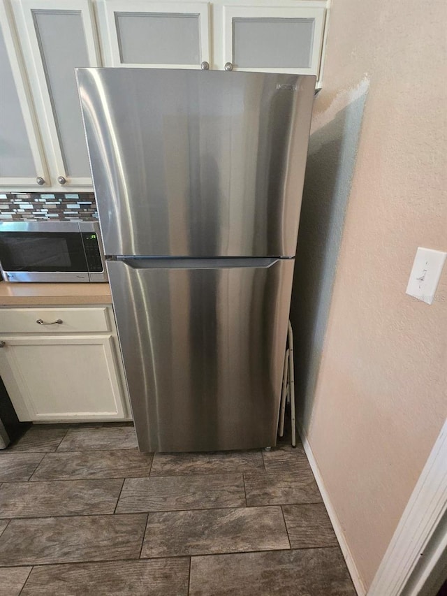 113 Guava Ter, Ocklawaha, FL 32179 - detailed view of stainless steel appliances, white cabinetry, and decorative backsplash