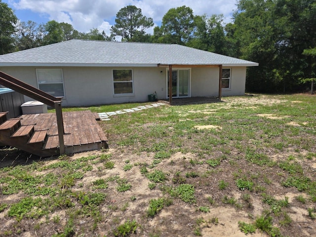 113 Guava Ter, Ocklawaha, FL 32179 - rear view of property with stucco siding, a wooden deck, a lawn, and roof with shingles