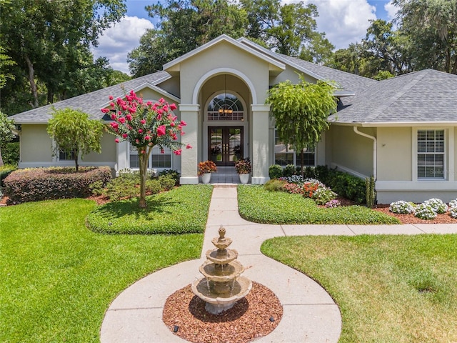 ranch-style home featuring french doors and a front lawn