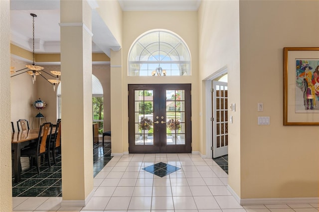 entrance foyer featuring french doors, light tile patterned floors, ornamental molding, and a high ceiling