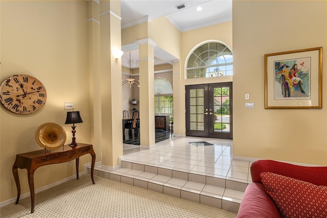 foyer entrance featuring ornate columns, crown molding, french doors, and a high ceiling