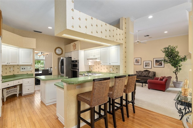 kitchen with backsplash, a kitchen breakfast bar, kitchen peninsula, white cabinetry, and stainless steel appliances