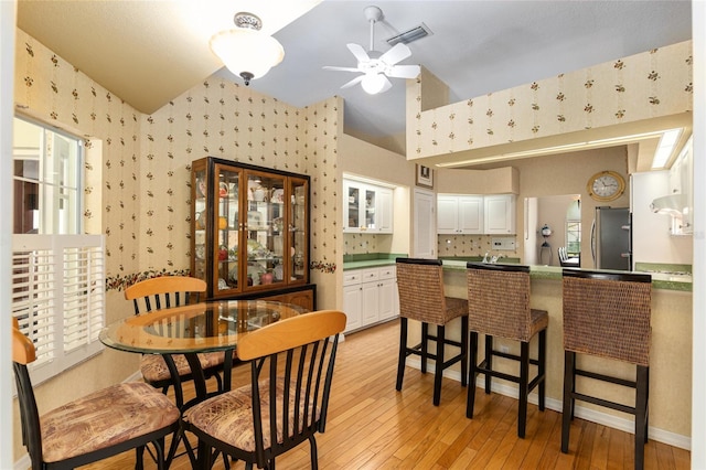 dining space featuring ceiling fan, light hardwood / wood-style flooring, and high vaulted ceiling