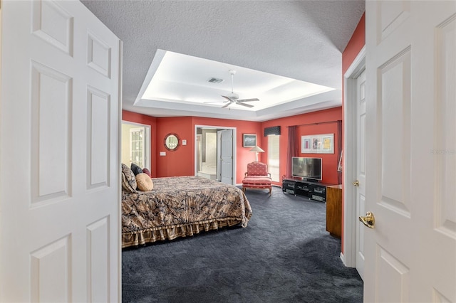 carpeted bedroom featuring ceiling fan, a raised ceiling, and a textured ceiling