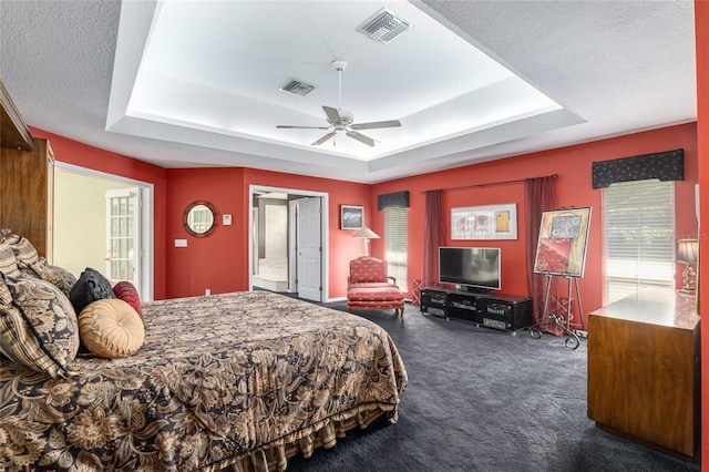 bedroom featuring a raised ceiling, ceiling fan, dark carpet, and a textured ceiling