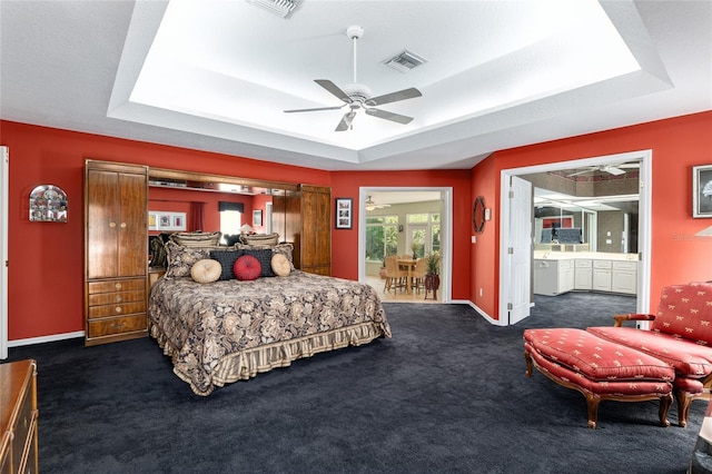 bedroom with ceiling fan, a raised ceiling, and ensuite bathroom