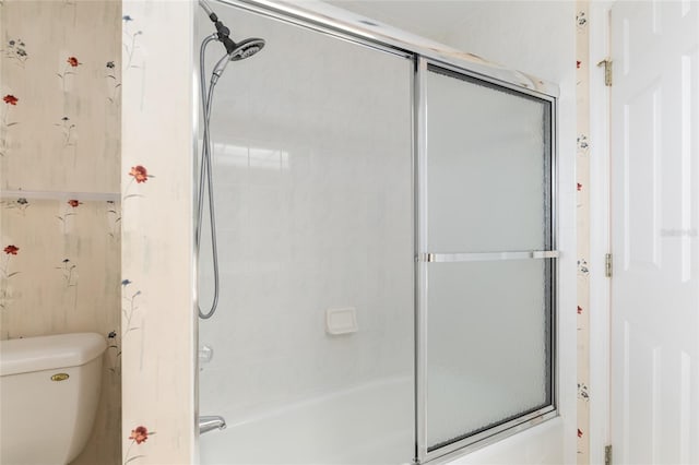 bathroom with combined bath / shower with glass door and toilet