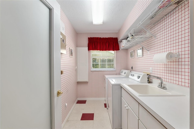 washroom with cabinets, a textured ceiling, washer and clothes dryer, sink, and light tile patterned floors