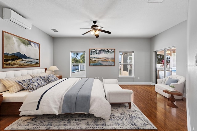 bedroom with a textured ceiling, ceiling fan, dark wood-type flooring, and a wall unit AC