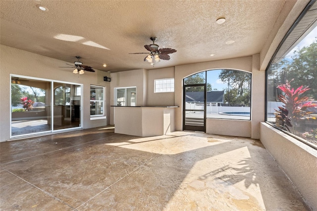 unfurnished sunroom with ceiling fan